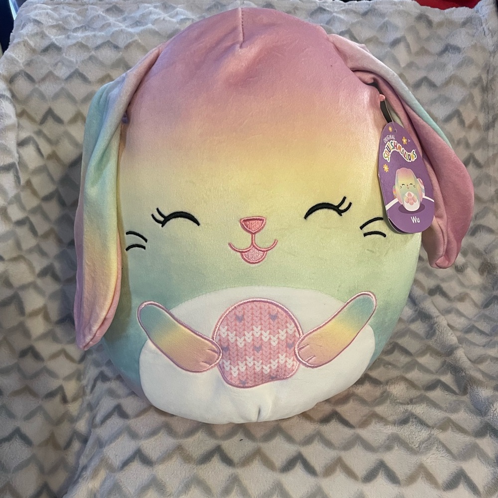 Squishmallows Wu the Rainbow Bunny plush holding an Easter egg stuffed animal to
